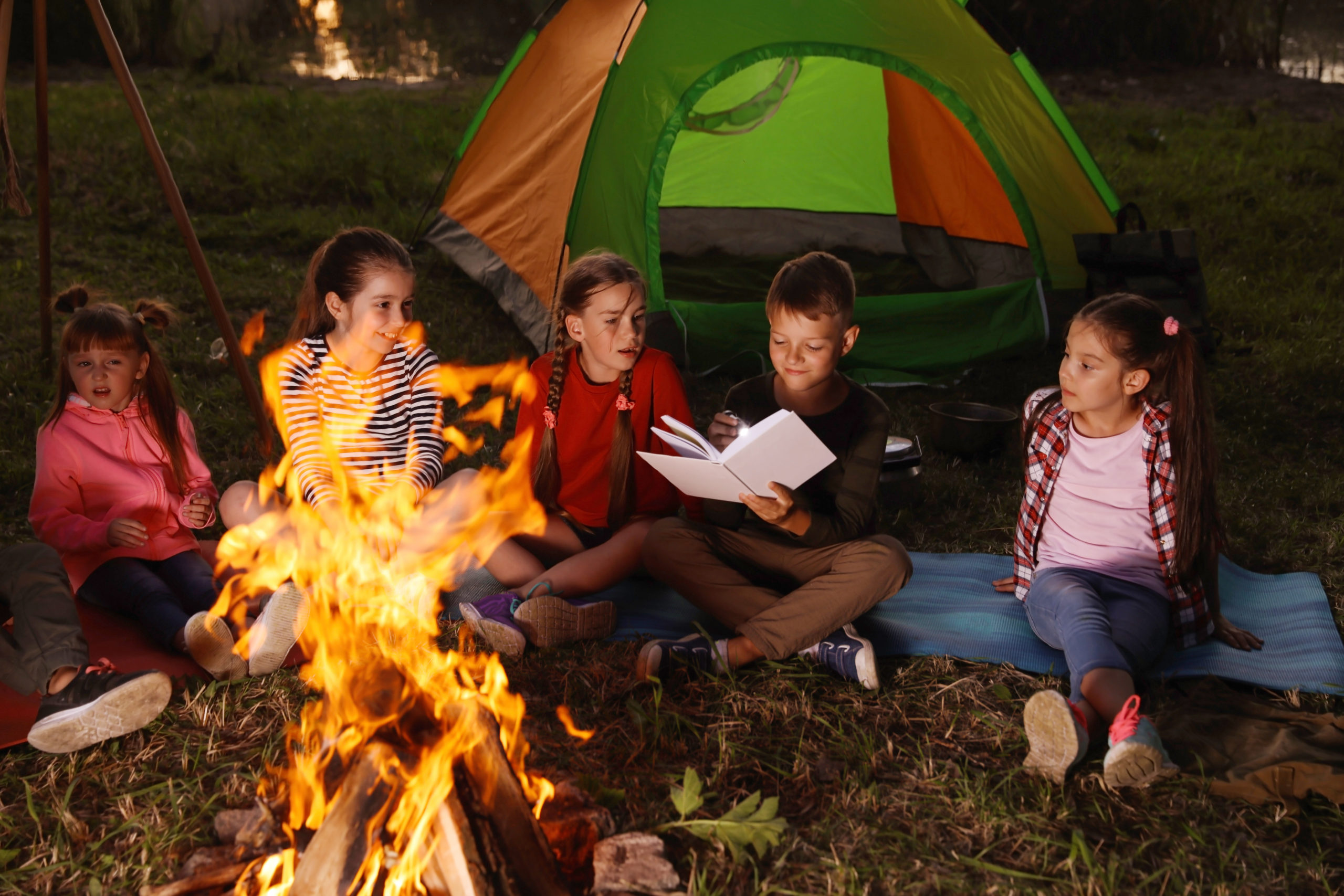 Campers reading around campfire